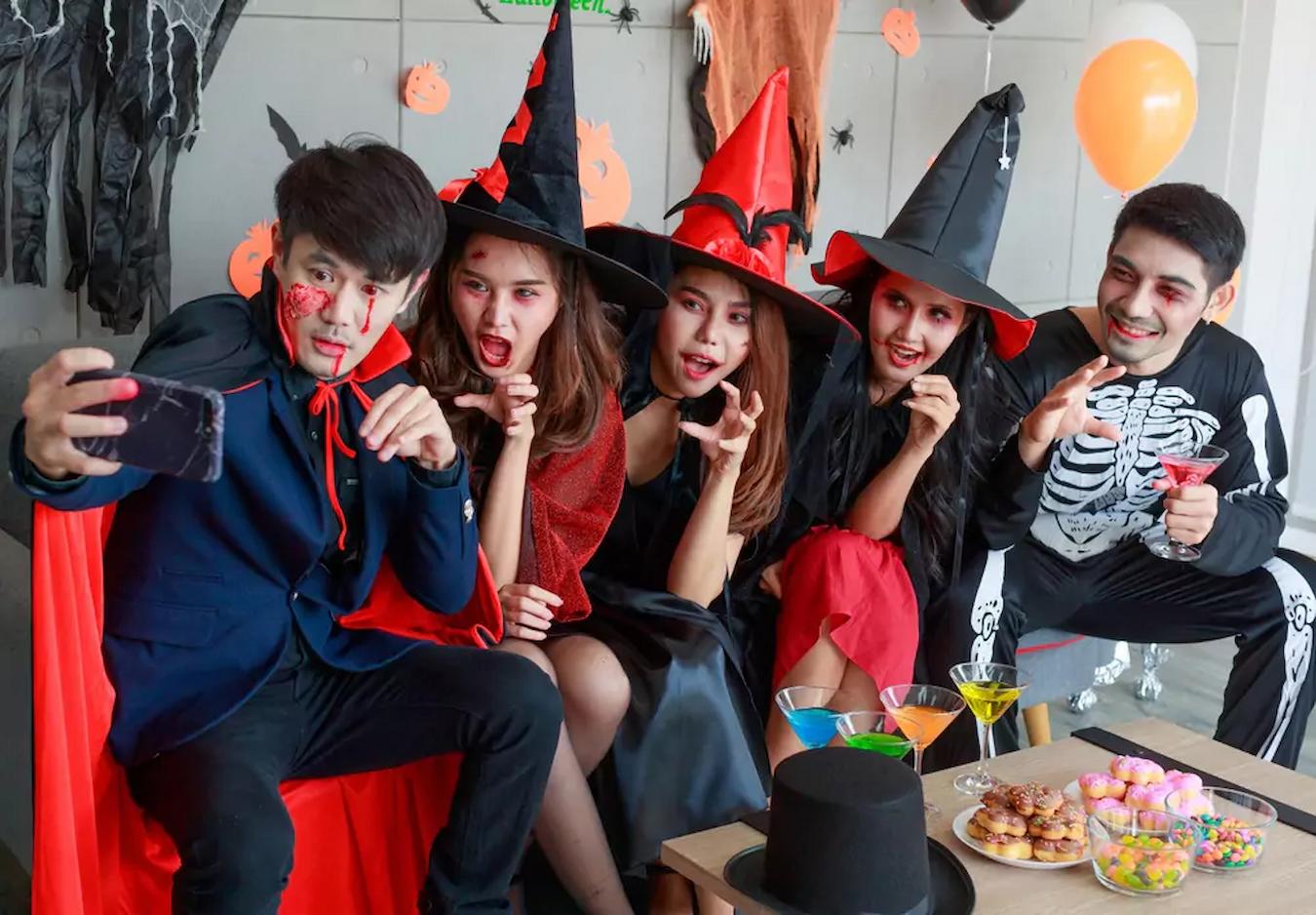 a group of people sitting together wearing halloween costumes co workers team building theme fun party