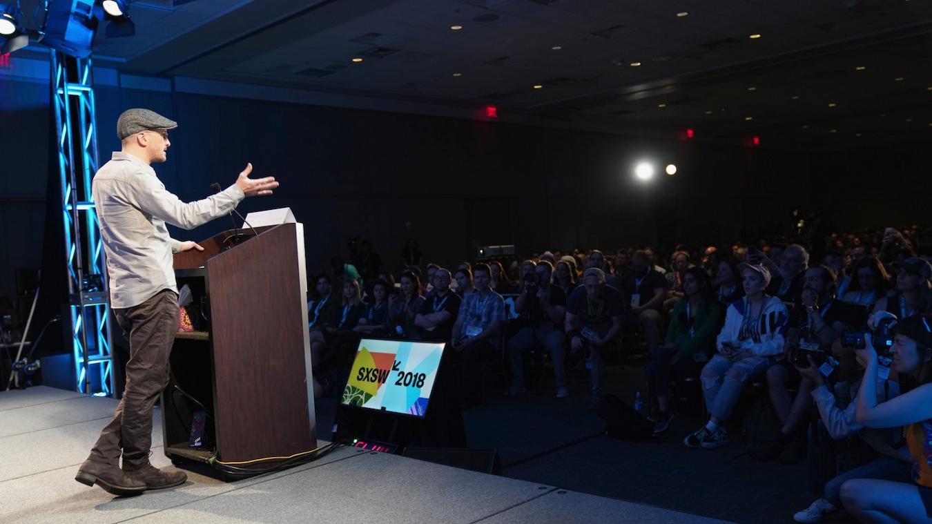 a man speaking on stage happen free run stage speakers create happen entire team production cues