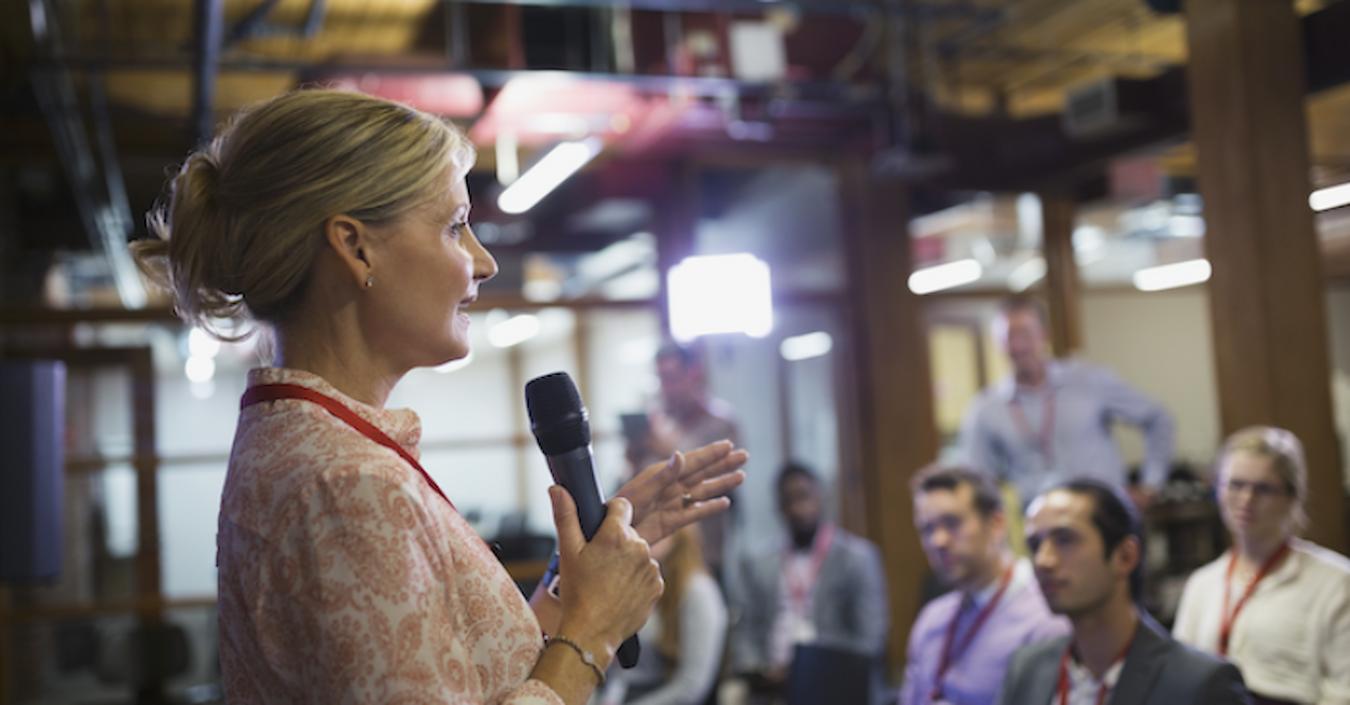 a woman speaking to an audience with a handheld mic hand held microphone types presentation skills speak loudspeakers helpful amplified proximity effect speak speech speaking stand talk microphone microphones microphone