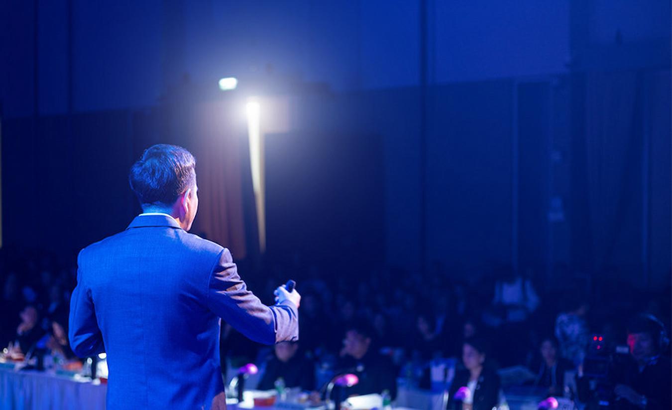 an event speaker talking to an audience enchanted forest ring toss happy hour s'mores bar neon lights big hit live band dress code wild west fresh fruit