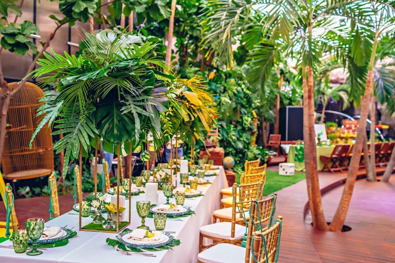 an outdoor event venue with tables with tropical decor and palm trees relay races catch fire local theater corporate event theme ideas