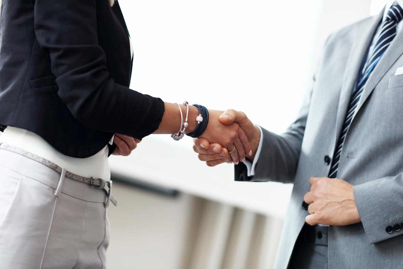 Colleague shakes hands with speaker who is presenting at organization