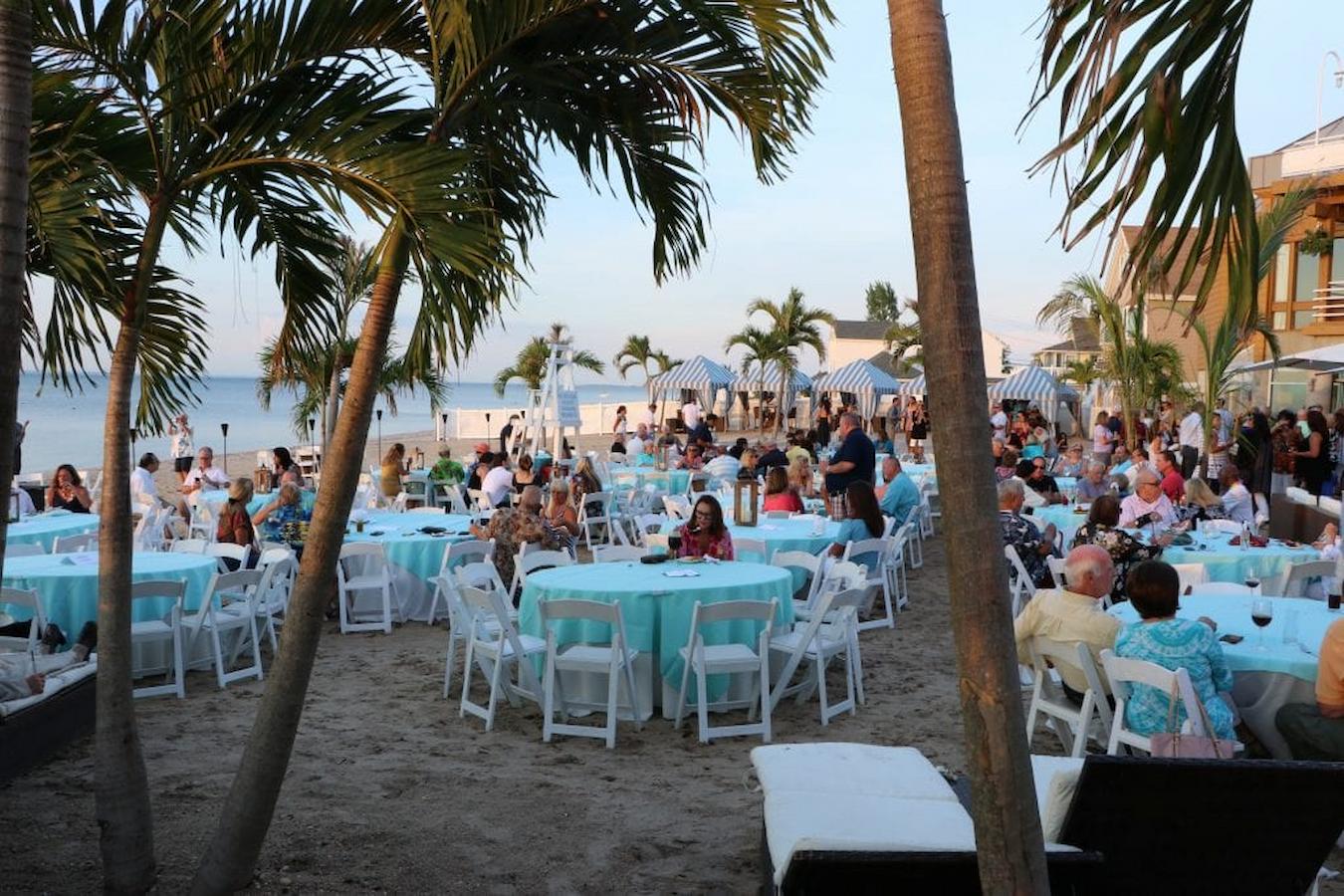 people at a formal beach event corporate party on the beach summer team building activities summer event summer company event random acts food trucks different teams cook off