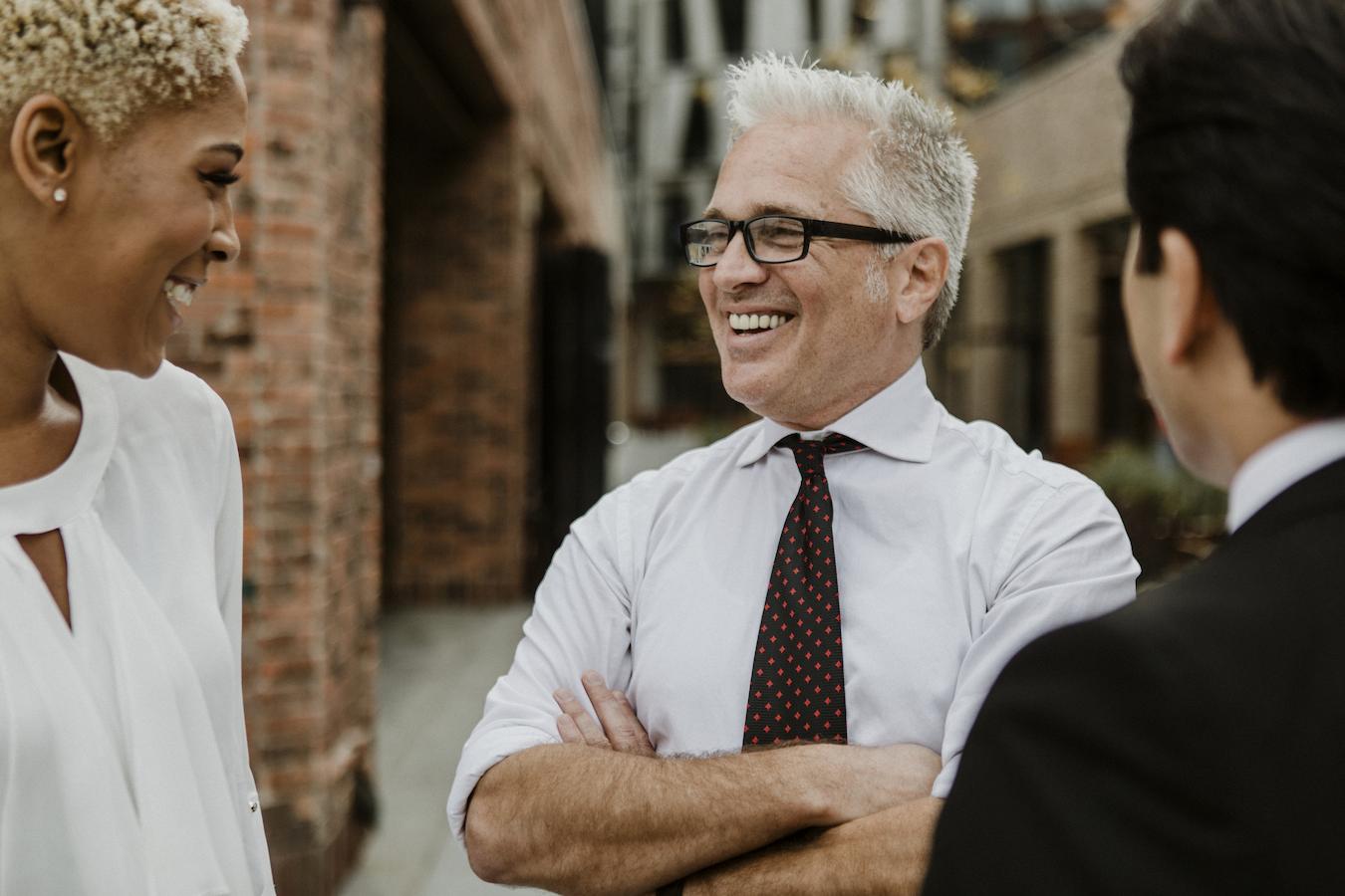Employees smile and have a conversation outdoors