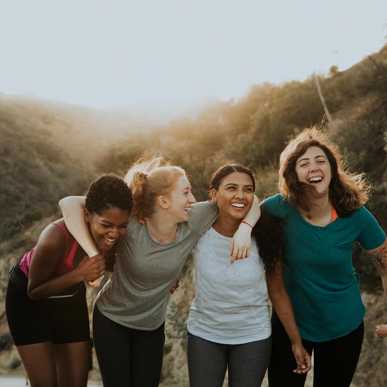 four girls laughing outside while hiking productive teams virtual happy hour virtual teams beach games random acts summer months escape room themes in person in person