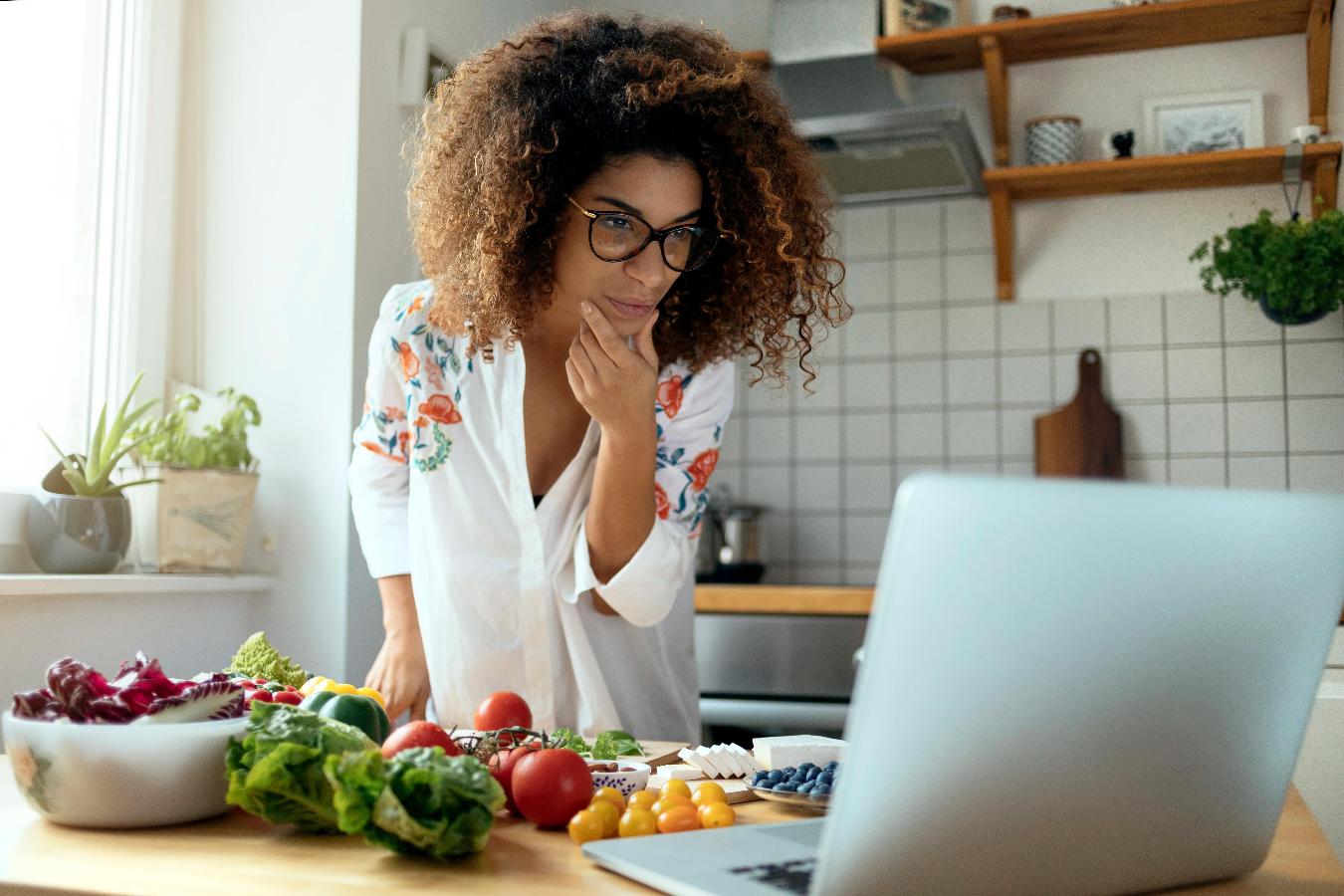 girl in her kitchen cooking with a laptop remote employees online team building ideas happy hour team meeting video call happy hour team morale virtual team events more team members video calls