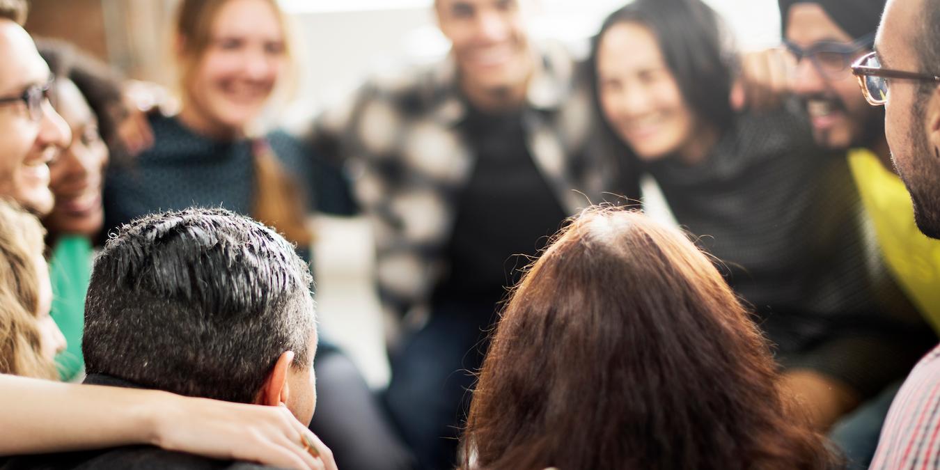 Group of people embrace and smile at each other in circle at workplace
