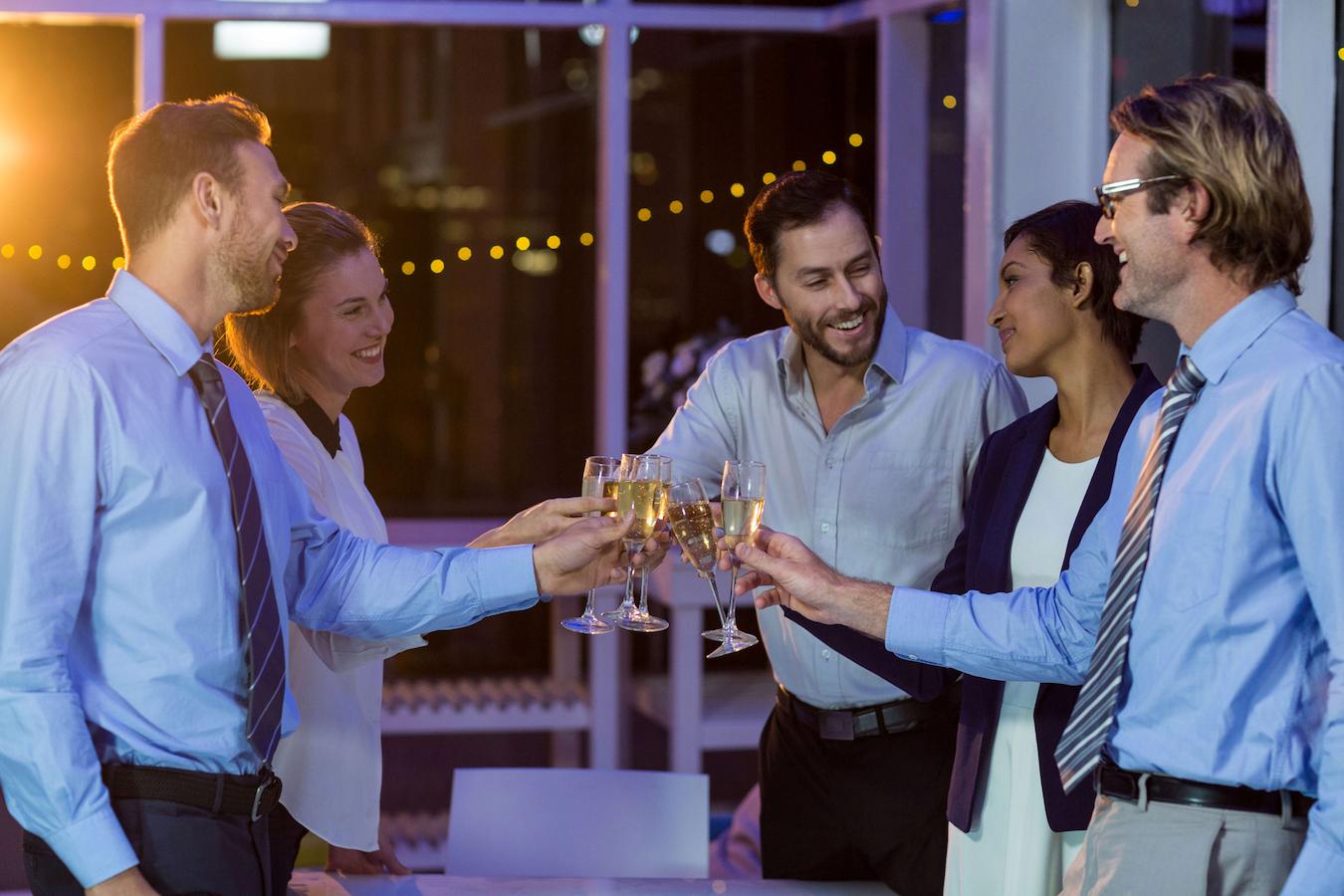 group of professionals clinking drinks and smiling local business in house content team vip guests promotional materials coordinate closely event logistics event day