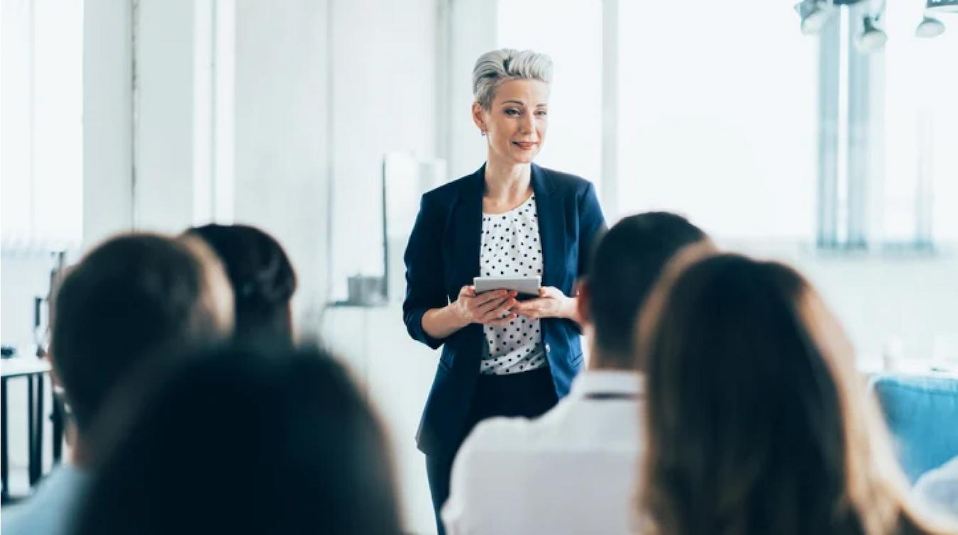 lady talking to a group of people with notecards stage presence important star power next song play musicians music super fan other artists person singing playing world band playing own performance audience member music