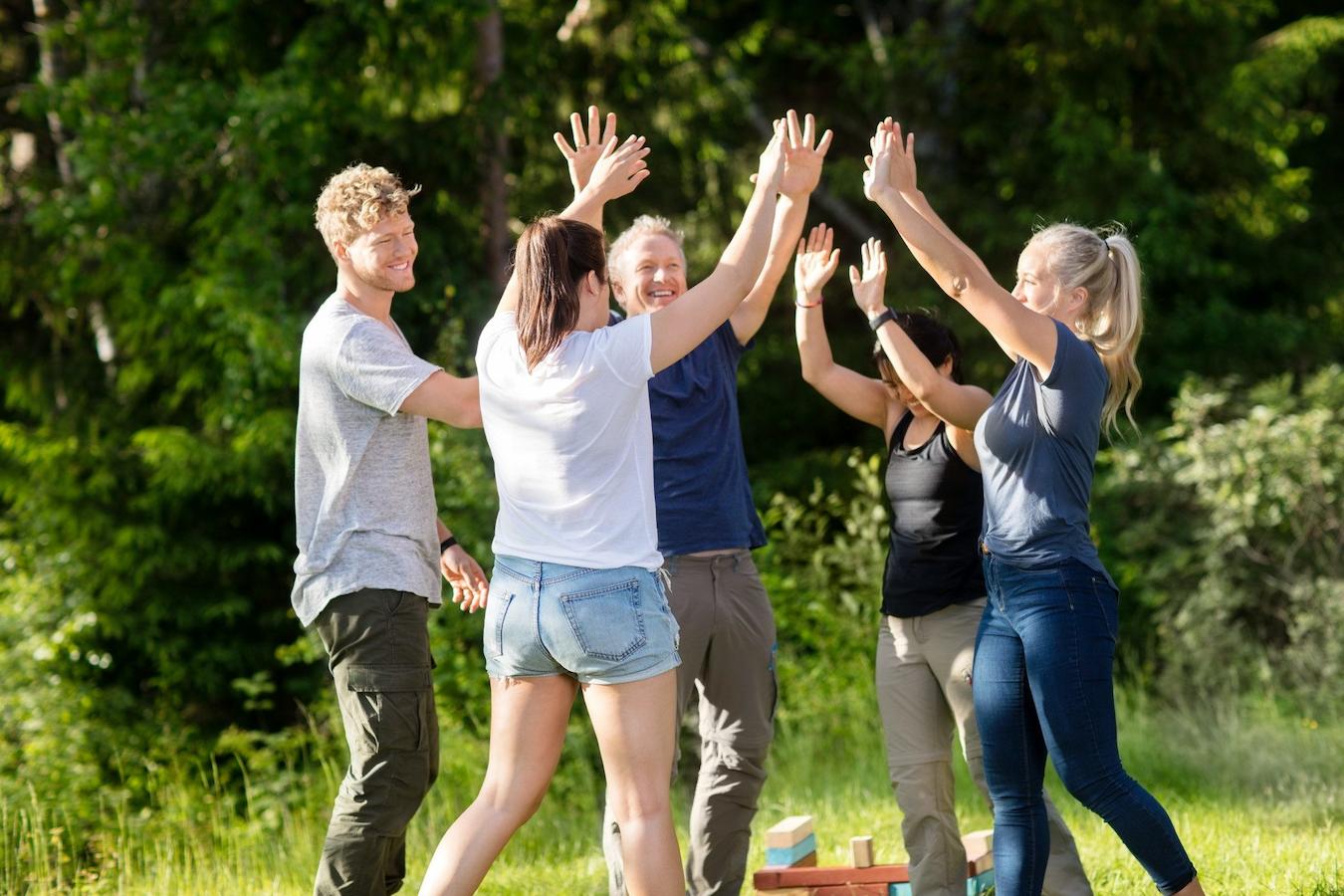 friends high fiving outside playing games nature retreat for summer outing lawn games ice cream food and drinks