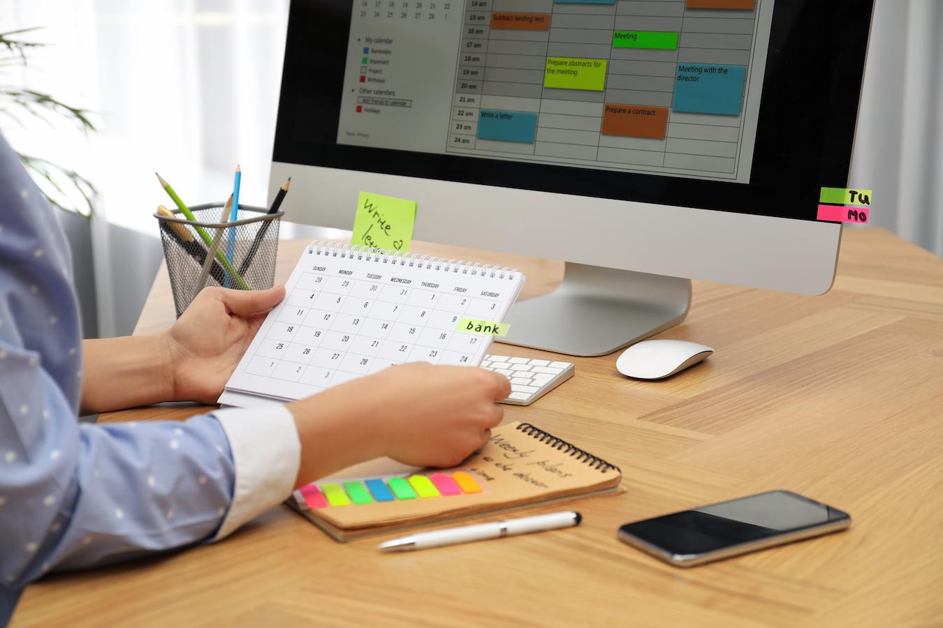 Person demonstrates employee productivity by using calendars and sticky notes as reminders