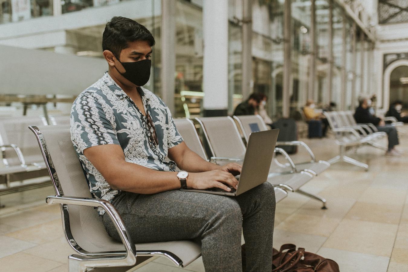 Person in floral button down sits at a station and works on their laptop