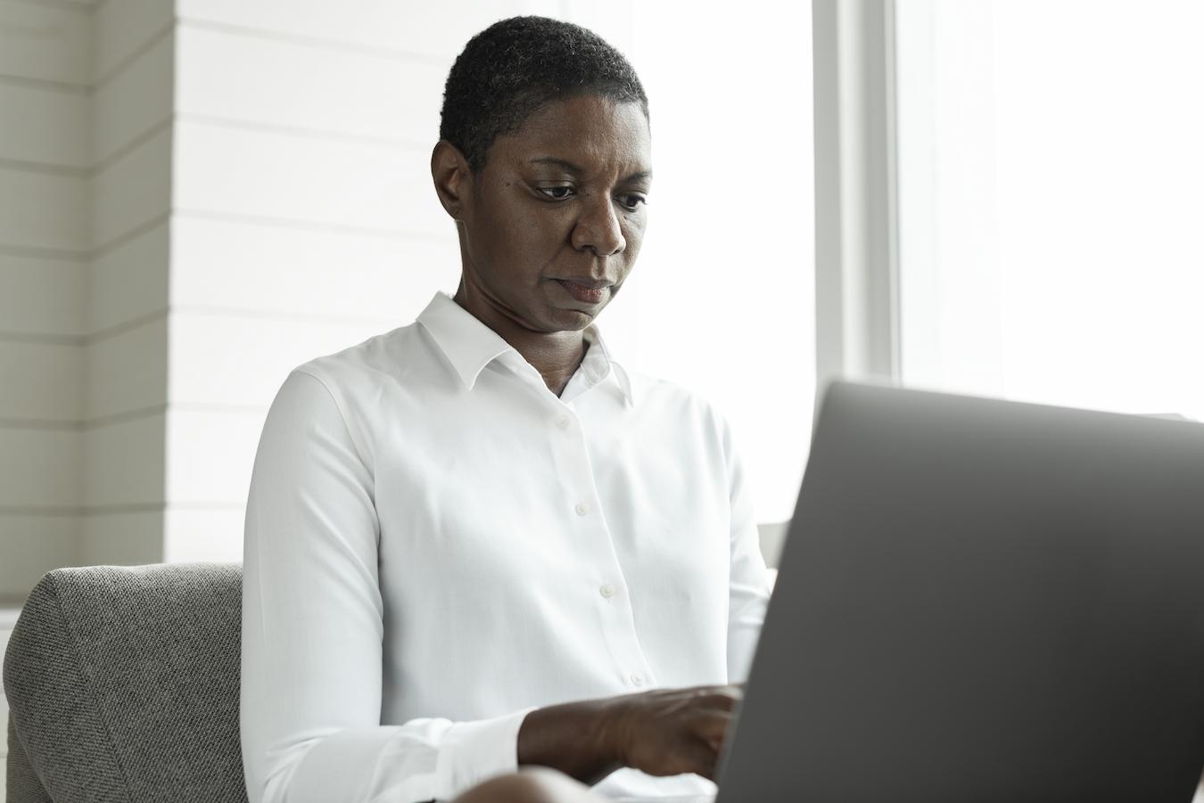 Person in white button down sits at desk and types on computer