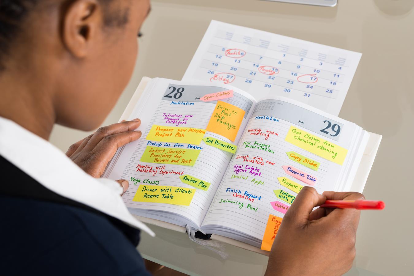 Person with great time management skills writes in their color coded planner