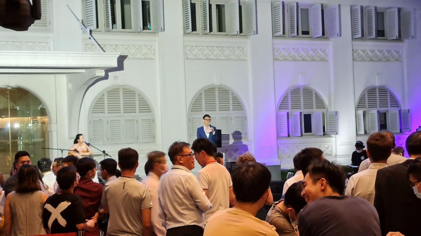 speaker hosting an event by white building in person in person virtual world board games remote teams in person whole team employee satisfaction