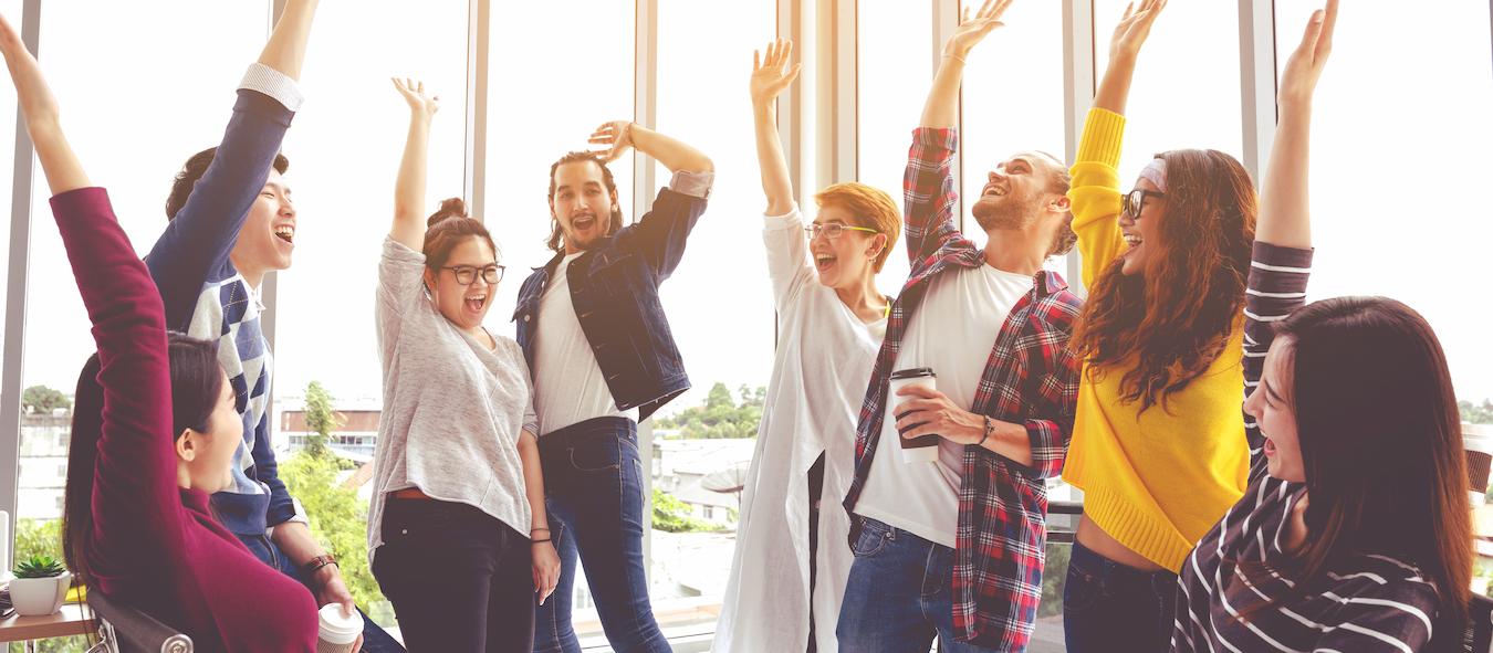 Teams show the benefits of team building as they excitedly raise their hands in collaboration