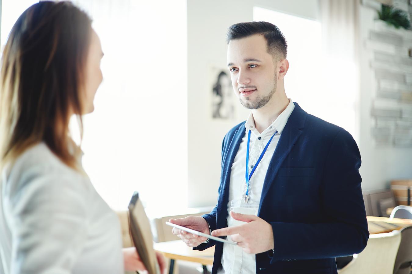 Two colleagues in office clothes chat at formal company event
