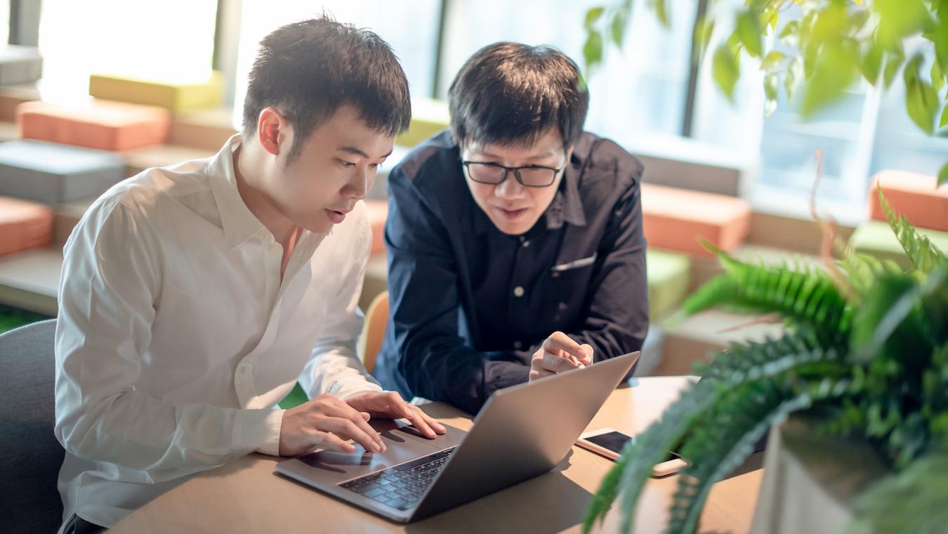 Two productive business colleagues look at computer and read about the average total output of their organization
