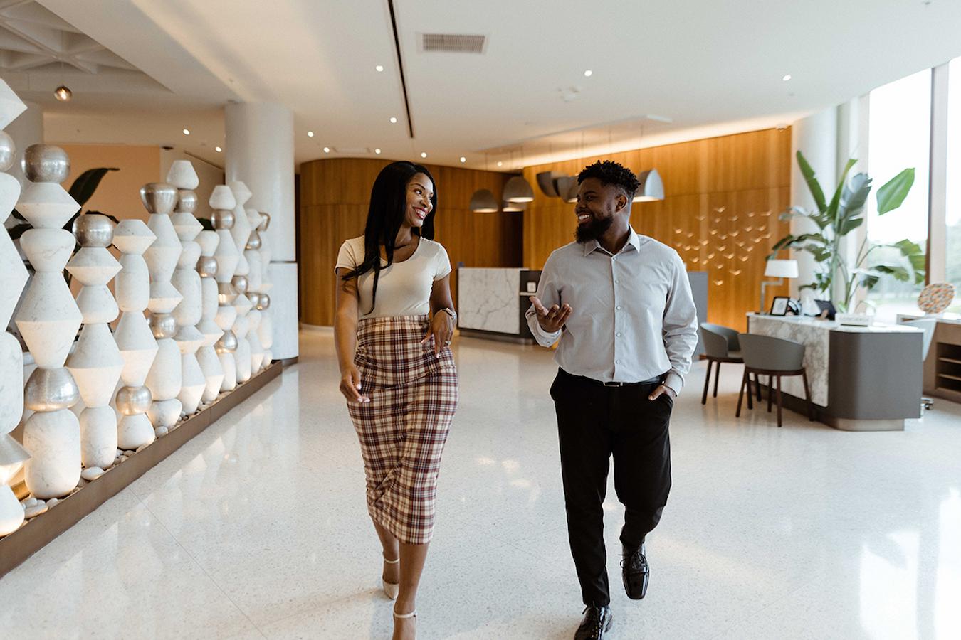 two professionals talking while walking down a hallway cost services goodwill stand stakeholders example partners budget existing clients team building sporting event corporate event guests stakeholders cost example community food budget