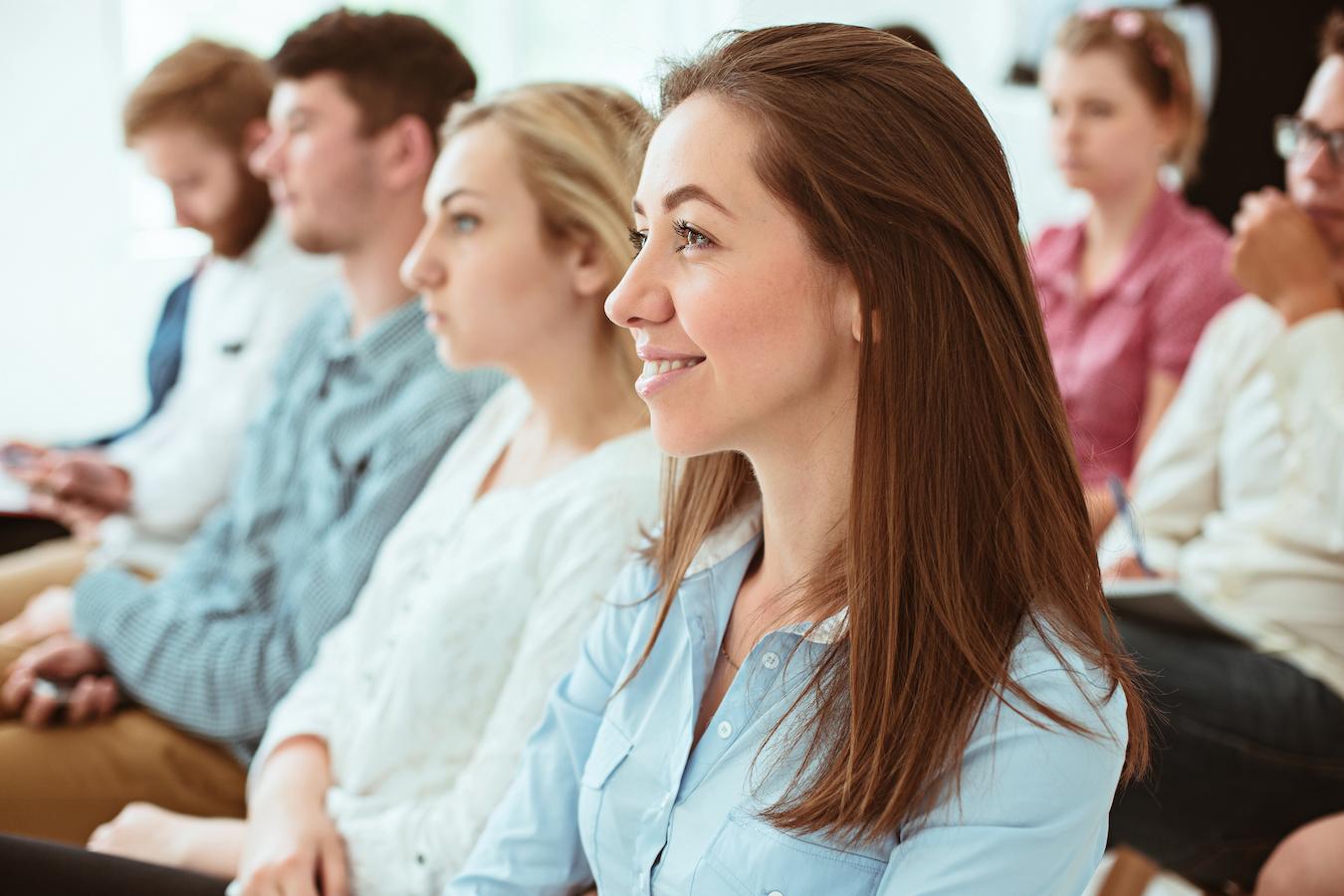 Woman in audience smiles at funny presentation in first few minutes of event